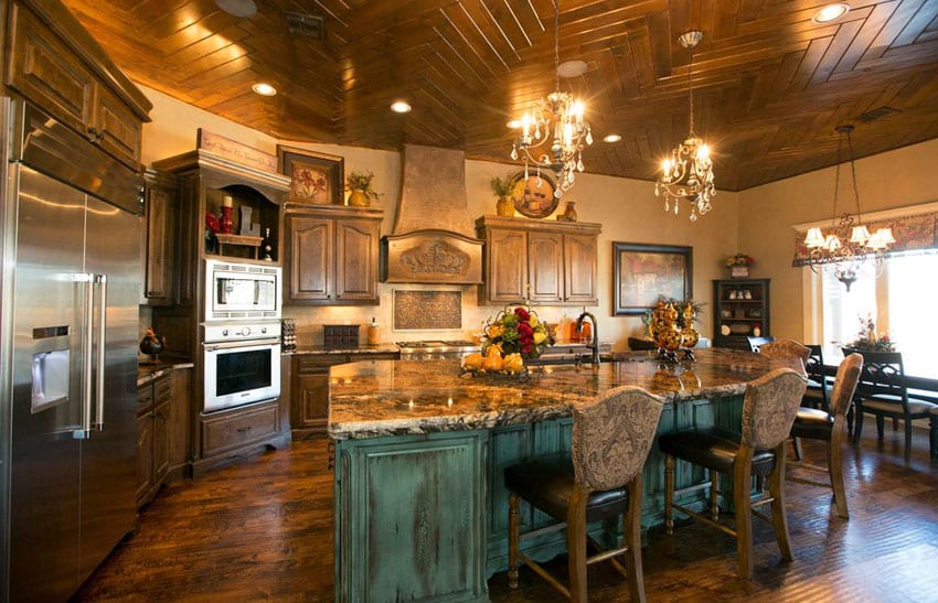 L-shaped kitchen with green distressed wood island and antique bar stools