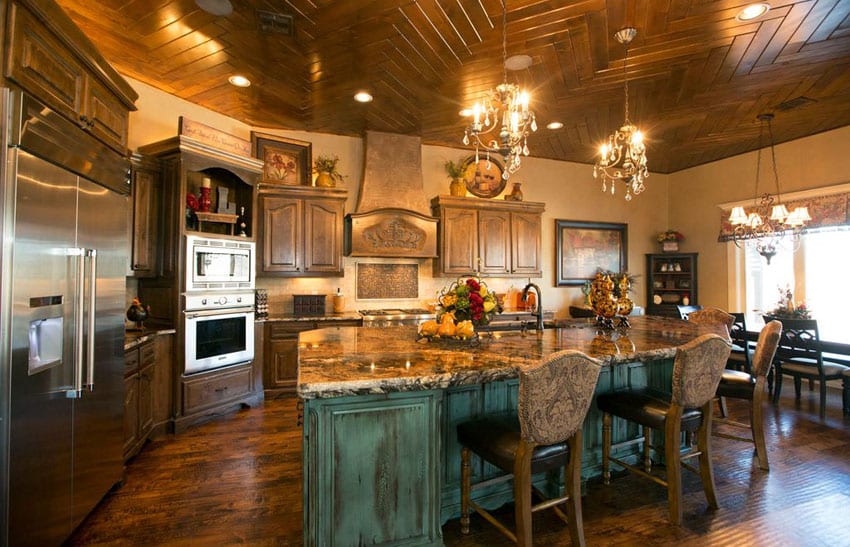 L-shaped kitchen with green distressed wood island and antique bar stools 