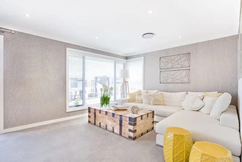 Living room with white sectional sofa light gray wallpaper and yellow end tables