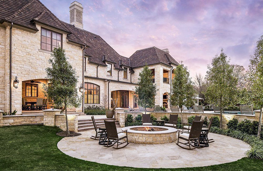 Luxury home backyard patio with round design and center stone fire pit