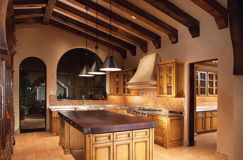Mediterranean kitchen with high open beam ceiling and solid wood countertop island