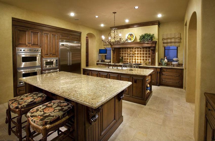 Mediterranean kitchen with rich wood cabinets, dark yellow painted walls, travertine floor and beige granite counters