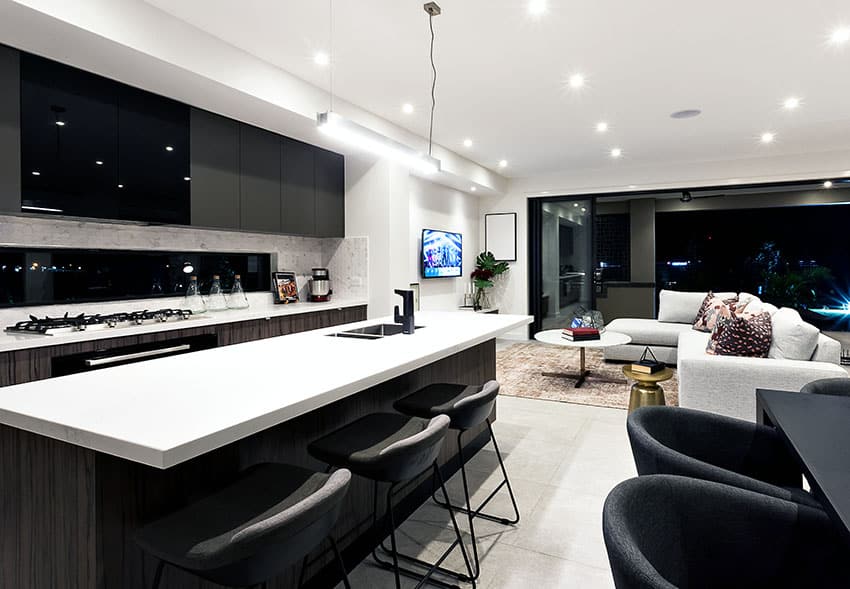 Modern kitchen with black cabinets white counters and breakfast bar