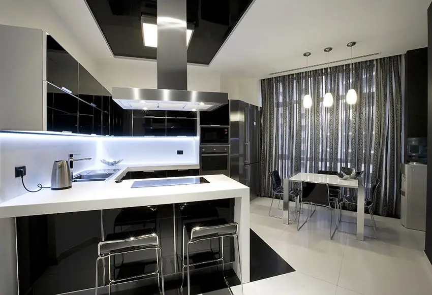 Modern kitchen with black high gloss cabinets white counters and dining peninsula