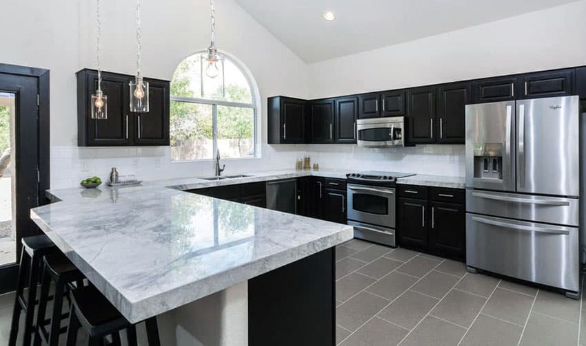 open plan kitchen with black cabinets and marble countertops