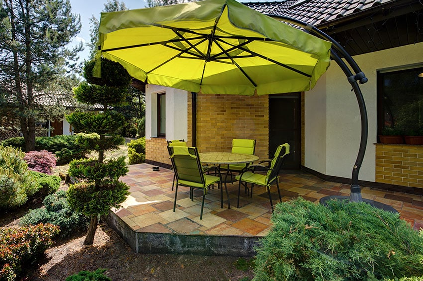 Raised slate patio in backyard with large umbrella shade