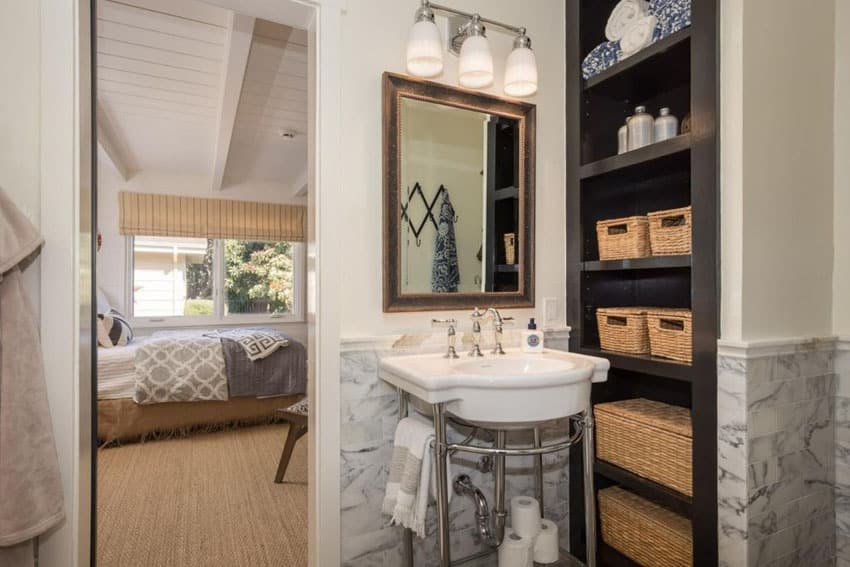 Small bathroom with pedestal sink and built in storage shelving with wicker baskets