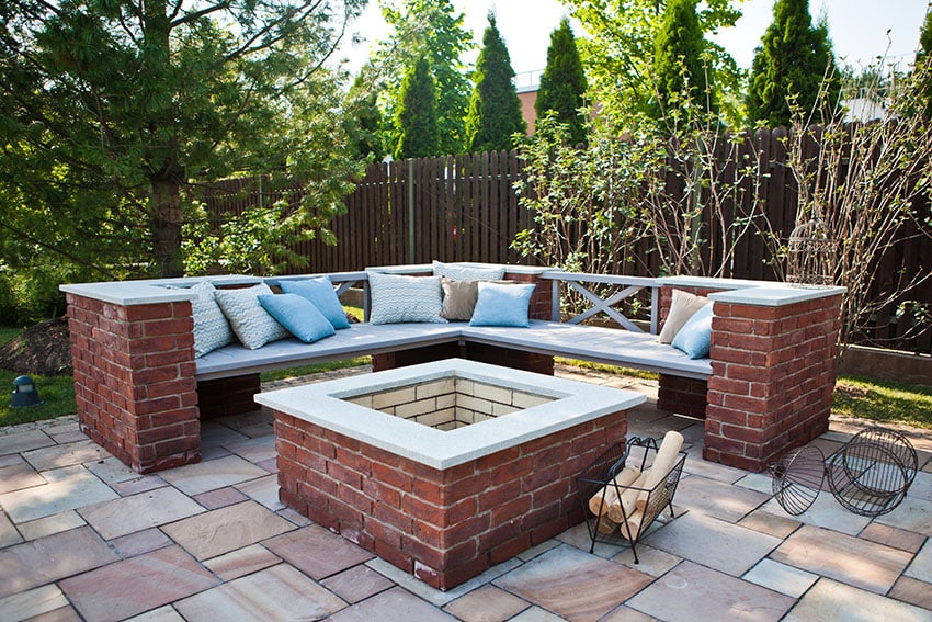 Stone tile patio with brick pit and bench in backyard