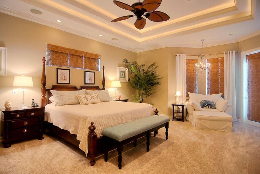Tan bedroom with matching carpet and tray ceiling with fan