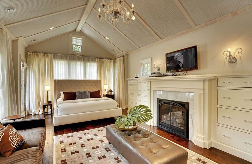 Tan contemporary master bedroom with vaulted ceiling fireplace and tufted bed