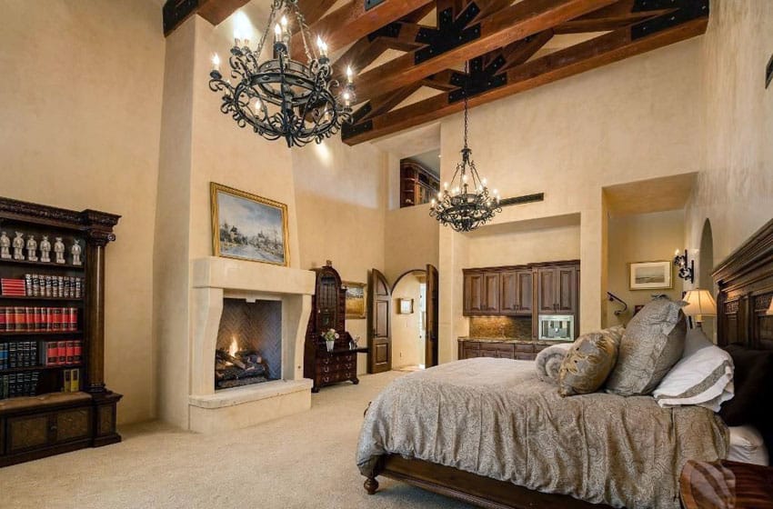 Tan Mediterranean bedroom with fireplace exposed beams and vaulted ceiling