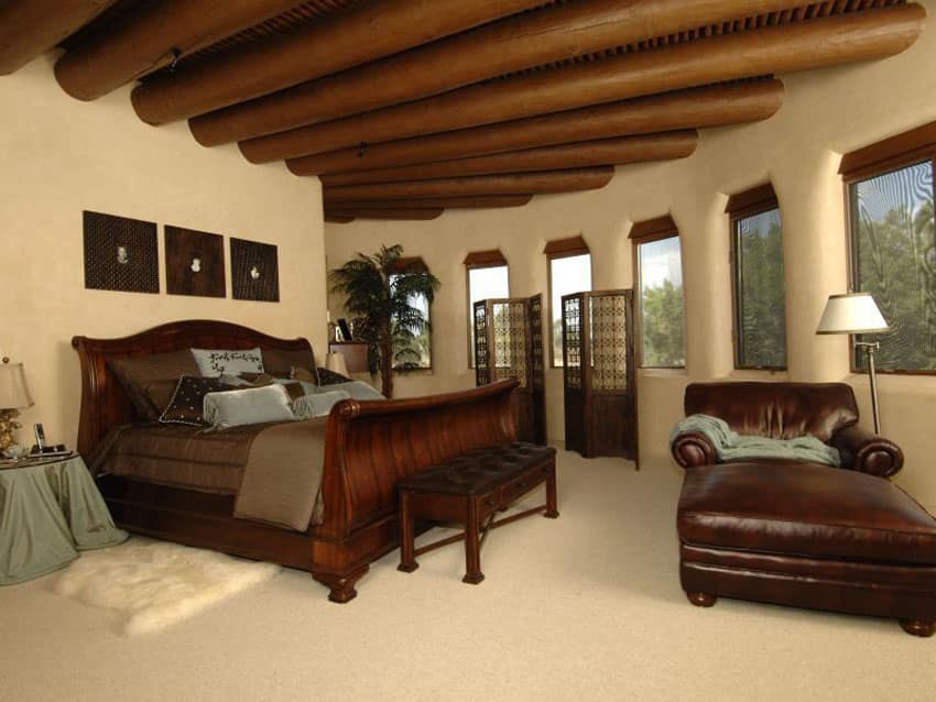 Tan Mediterranean style bedroom with round exposed beam ceiling