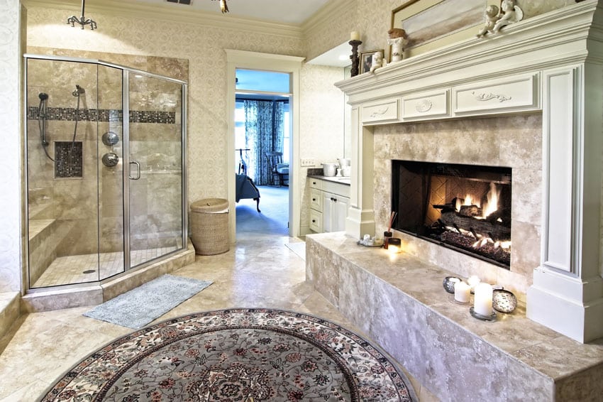 Bathroom with wide fireplace, decorative tile and glass enclosed shower with bench