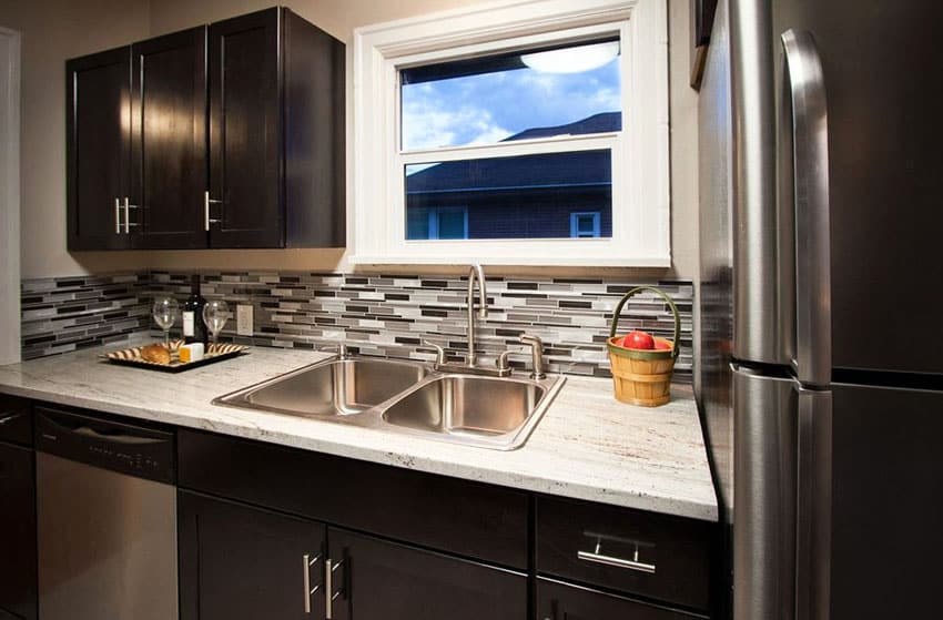 Kitchen with deep toned cabinetry with glass mosaic tile backsplash