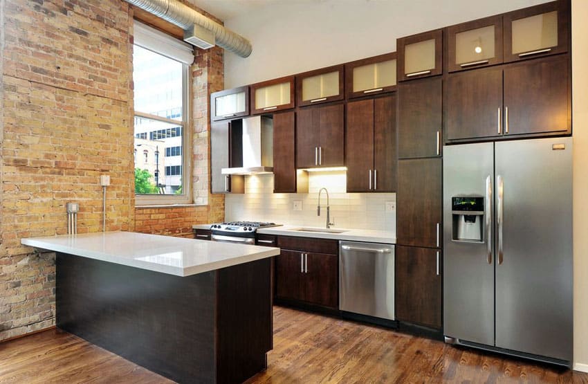 Kitchen with dark brown cabinets, white quartz counters and exposed brick walls