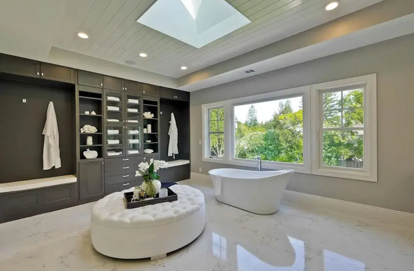 Contemporary master bathroom with freestanding acrylic tub, skylight and tufted ottoman