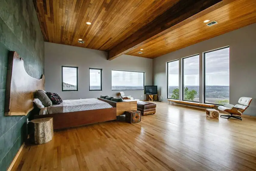 Bedroom with oak ceiling, green accent wall and picture windows