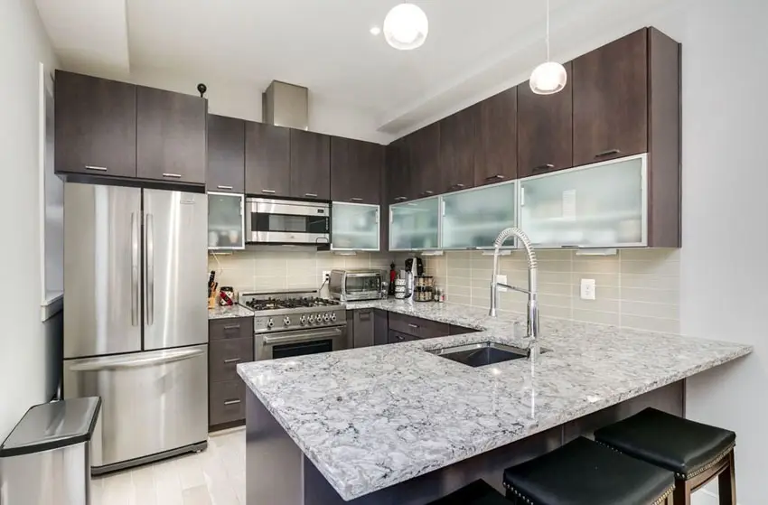 J shaped kitchen with black and white quartz countertops and dark brown cabinets