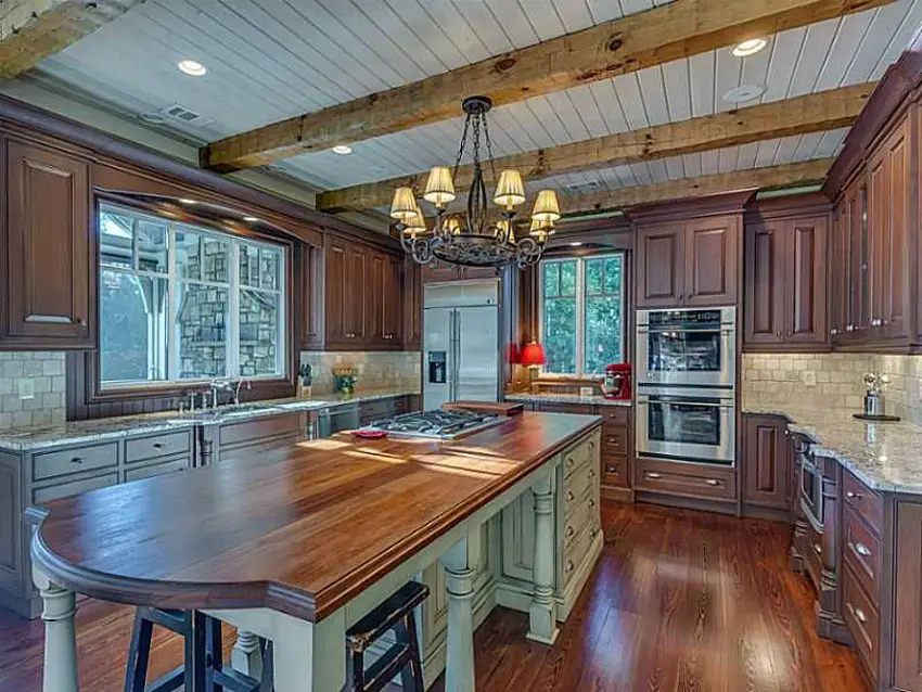 Country kitchen with wood countertop island with white base and beadboard ceiling