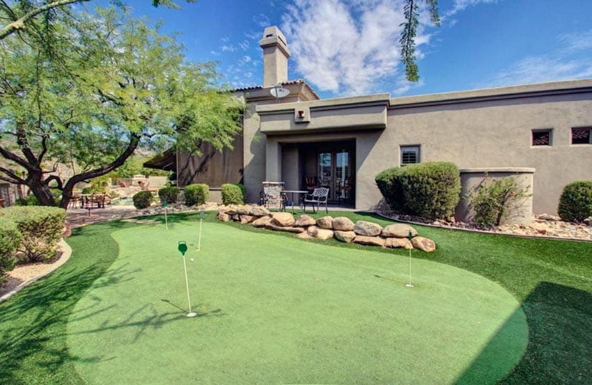 Large backyard putting green with rock landscaping