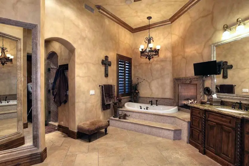 Mediterranean style luxury bathroom with enclosed tub, fireplace, dark wood vanity and limestone floors