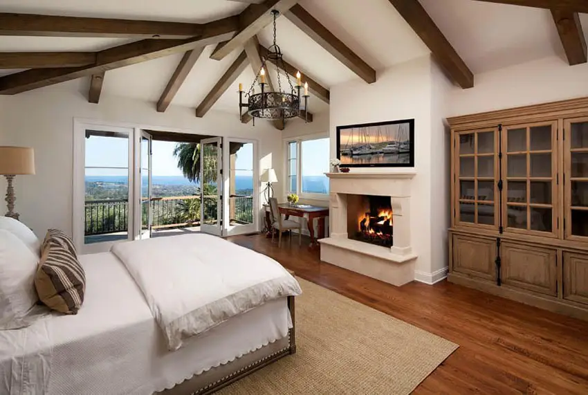 Mediterranean style master bedroom with red oak flooring, chandelier and balcony views