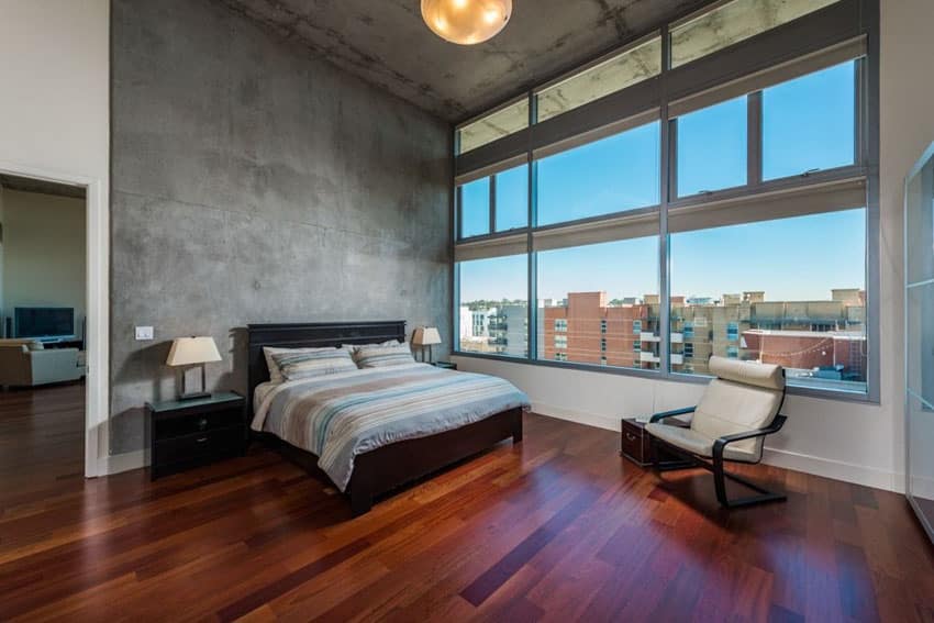 Bedroom with Brazilian cherry lumber floors and concrete walls