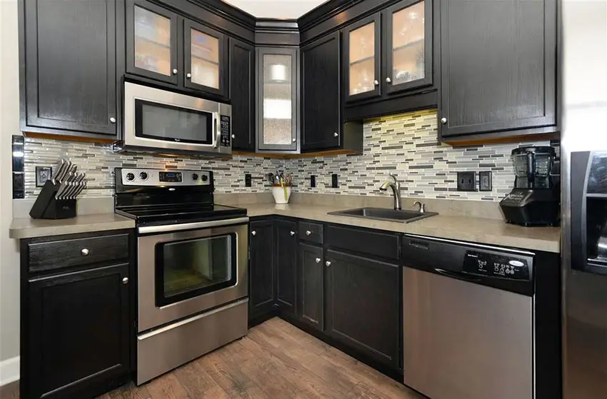 Kitchen with black kitchen cabinets with lighting inside and matchstick mosaic tiles for the backsplash