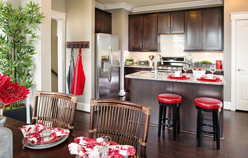 Small traditional kitchen with island dark cabinets, light granite counters and red bar stools