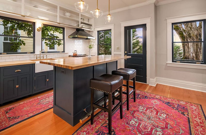 Kitchen with butcher block countertops, red area rug and windows