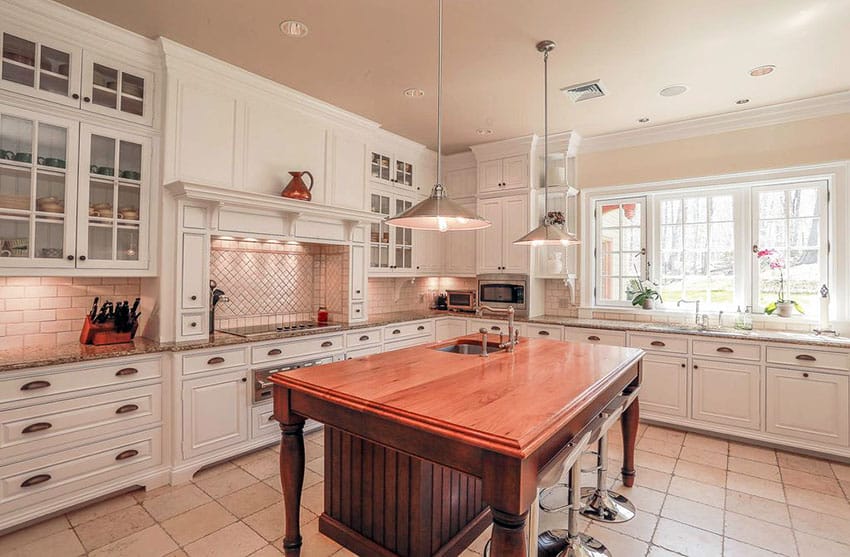 Traditional kitchen with white cabinets with glass doors and wood island with beadboard cabinet