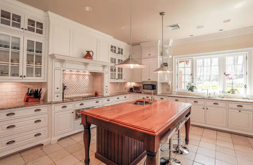Traditional kitchen with white cupboards with glass doors and wood island with beadboard 