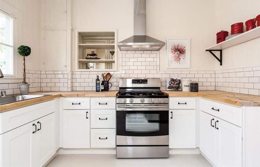 White cabinet kitchen with wood countertops and subway tile
