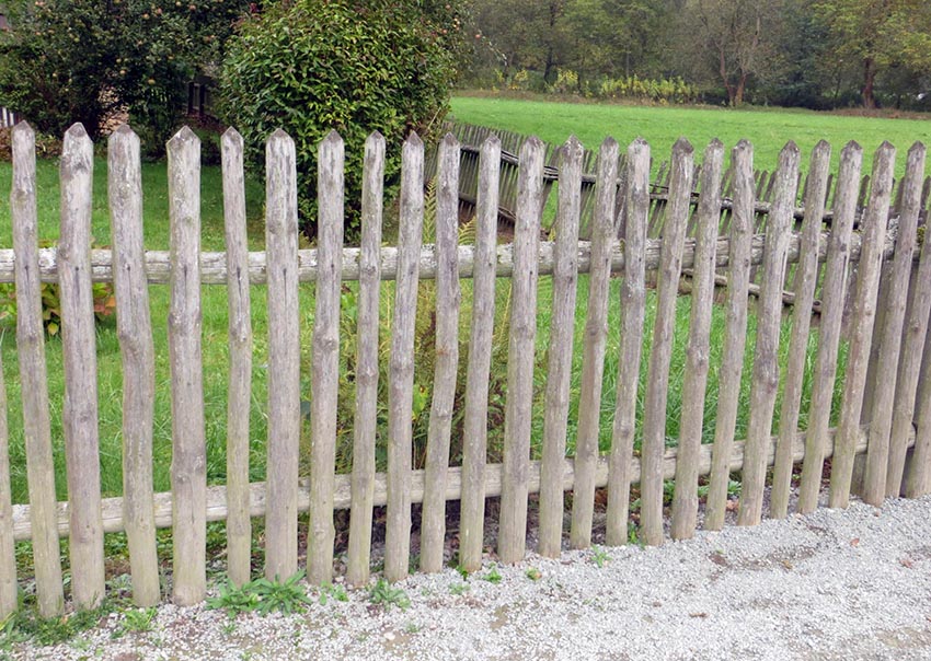 Untreated wood stockade fence with rough cut stakes and horizontal posts