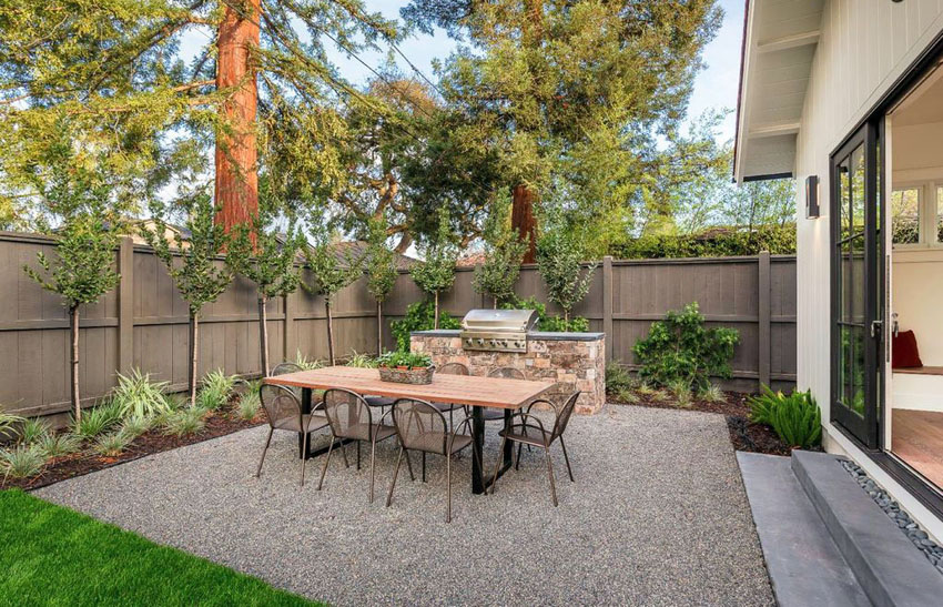 Backyard gravel patio with dining table and outdoor kitchen