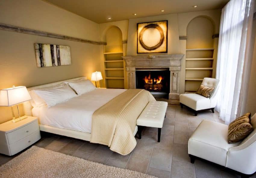 Beautiful beige color bedroom with alcoves next to fireplace and stone mantel