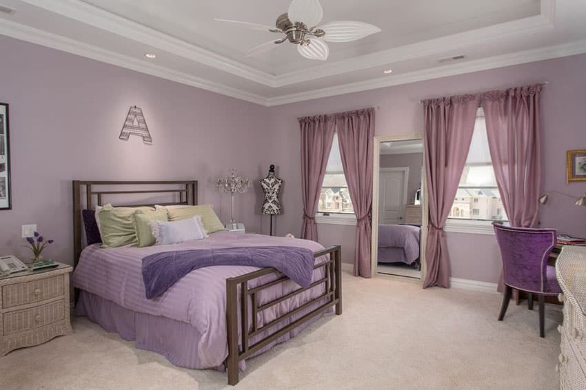 Beautiful purple womens bedroom with white tray ceiling and beige carpet