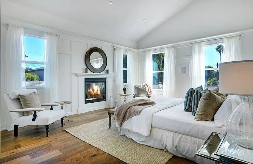 Beautiful white master bedroom with fireplace and wood flooring