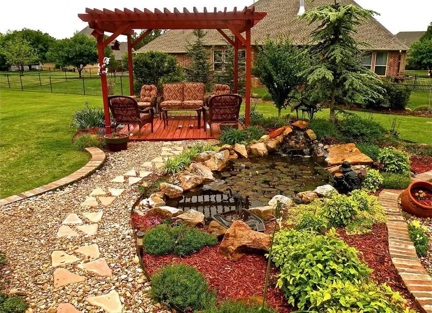 DIY paver and gravel walkway to backyard pergola next to small pond with fountain