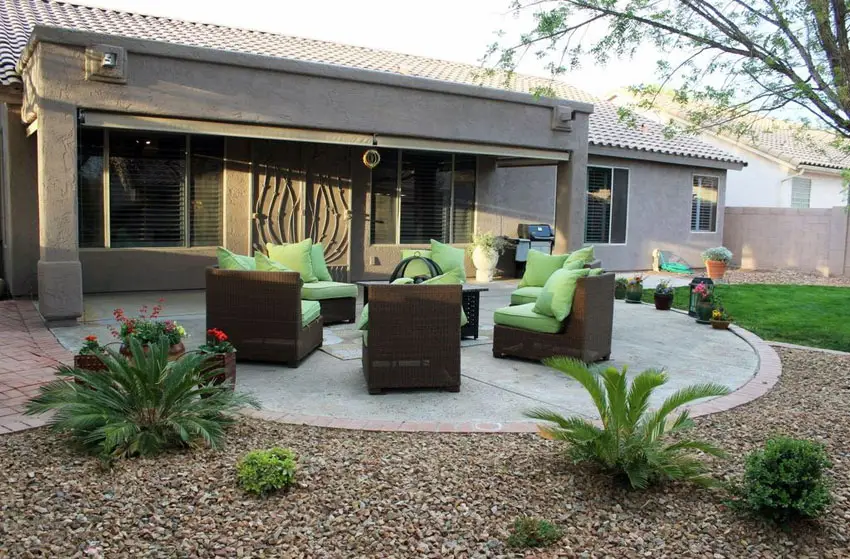 Gravel and brick patio and green chairs with green cushions