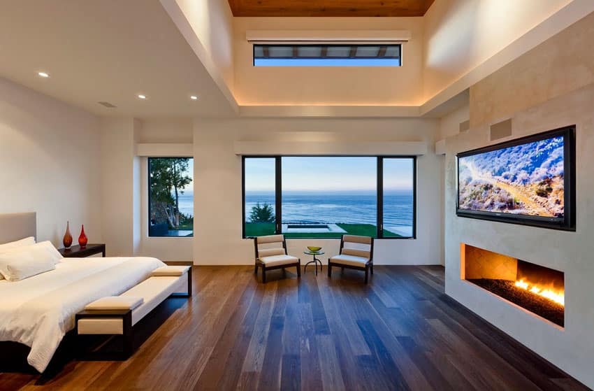 Contemporary bedroom with fireplace and water view