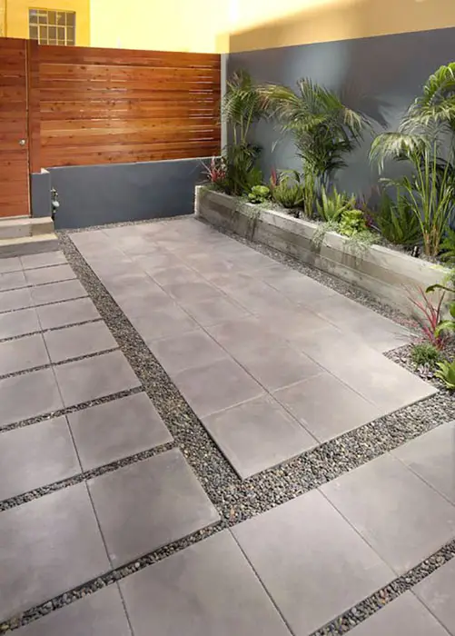 Patio with square concrete pavers, gravel fillers and a wooden gate
