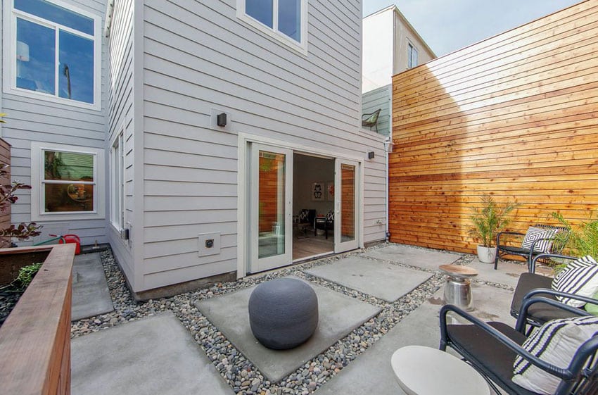 Contemporary concrete and river rock patio with large privacy fence