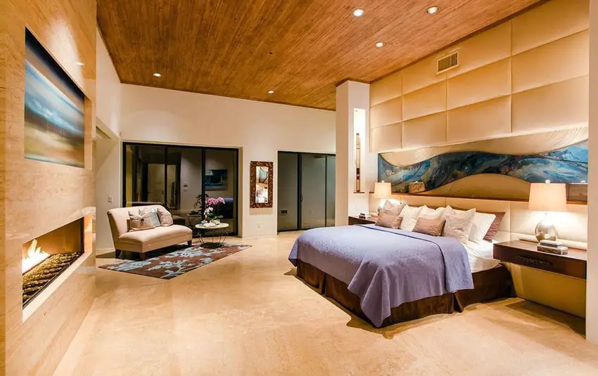 Contemporary master bedroom with fireplace and padded wall bed headboard