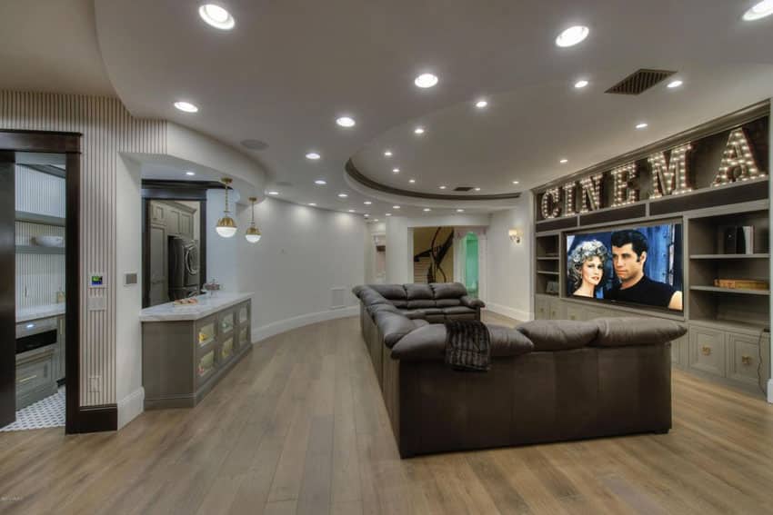 Contemporary movie room basement with wood flooring and built in bookshelves