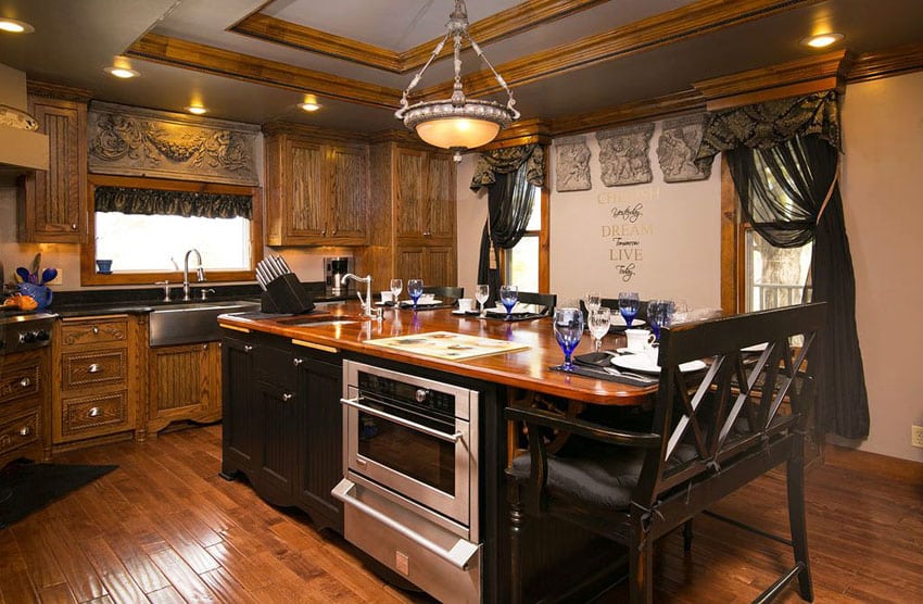Dark wood custom cabinet kitchen with butcher block island with high backed dining bench
