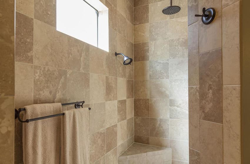 Inside a travertine shower with rainfall shower and small bench