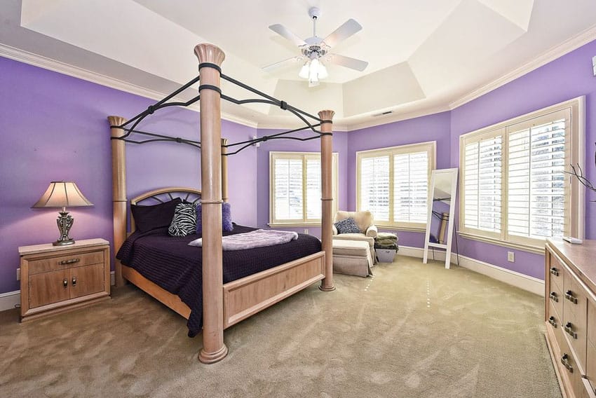 Light purple bedroom with tray ceiling beige carpet and four post bed