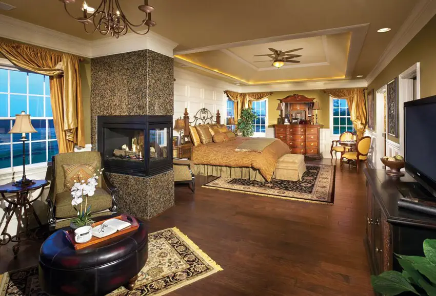Luxury master bedroom with peninsula fireplace hardwood flooring and sitting area