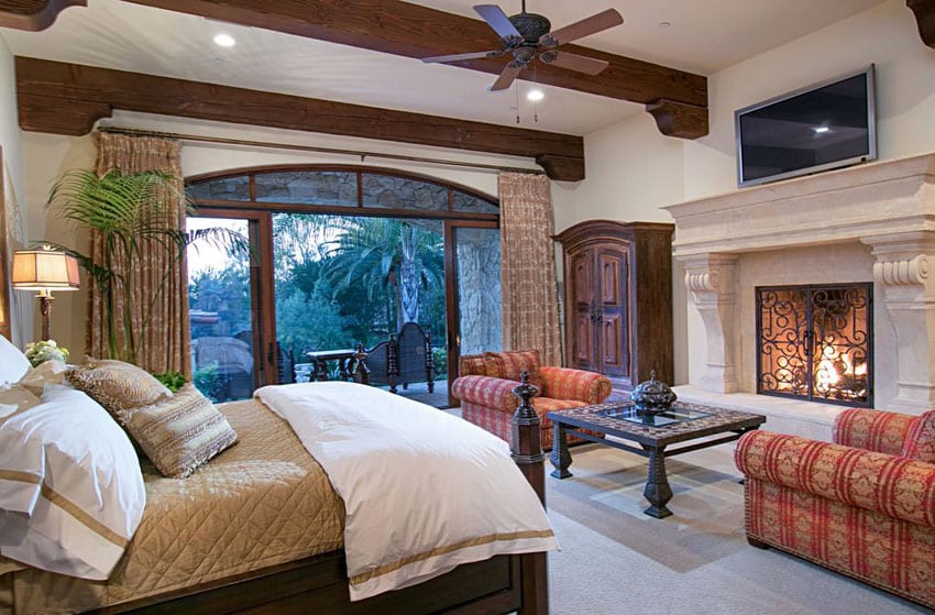 bedroom with plaster fireplace, wood beam ceilings and outdoor balcony